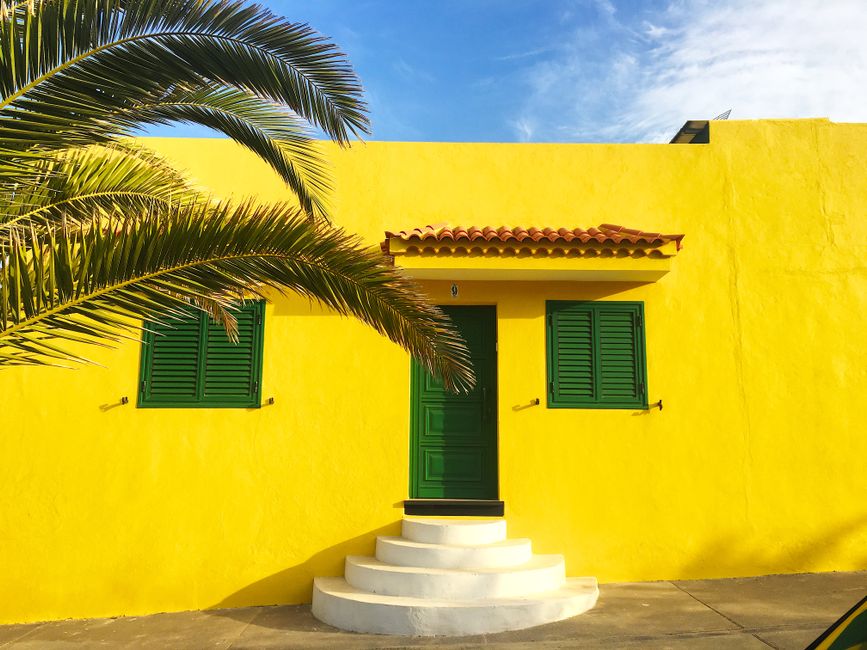 Yellow painted house wall with green shutters.
