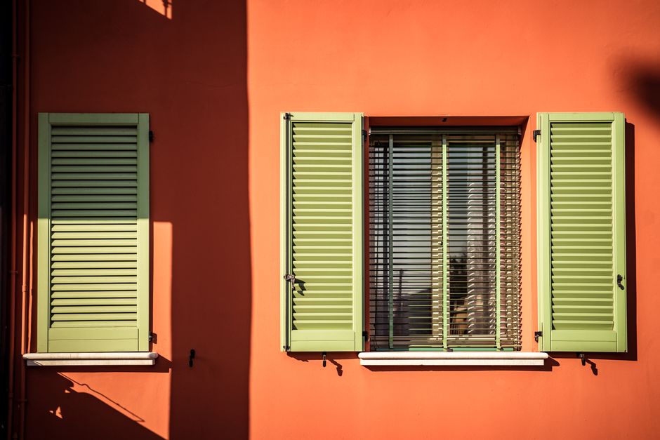 Green shutters against an orange painted wall.