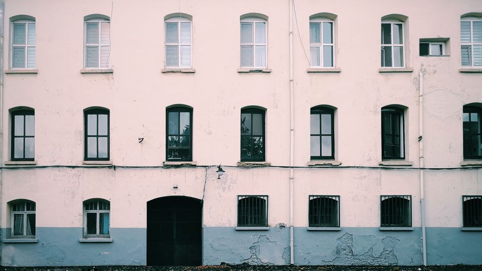 Painted exterior wall of an older house with symmetrical windows.